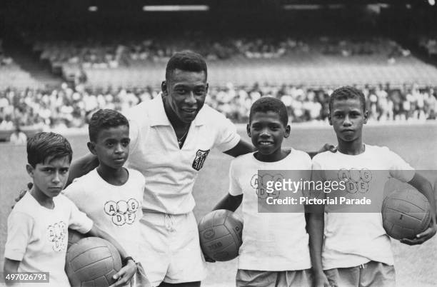 Brazilian footballer Pele lining up in his Santos FC kit with a group of boys wearing Olympic logo t-shirts, circa 1970.