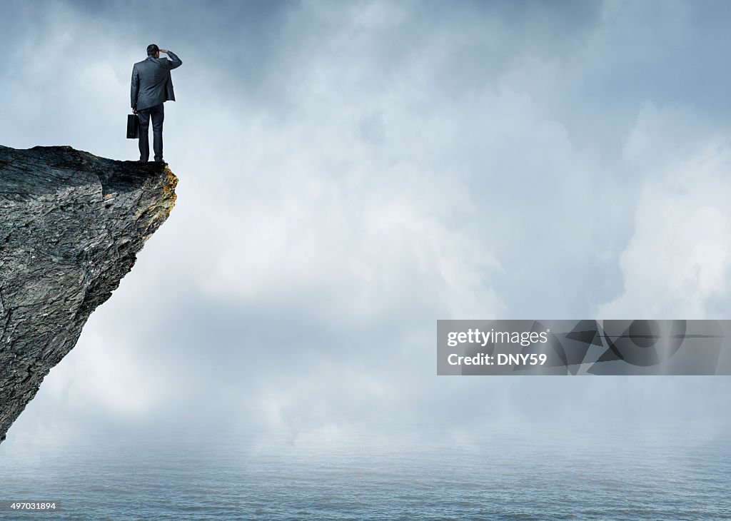 Businessman Peering Out To Sea