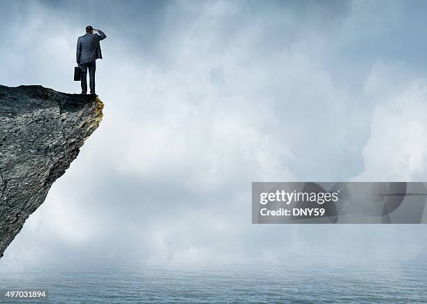 businessman peering out to sea - edge of cliff stock pictures, royalty-free photos & images