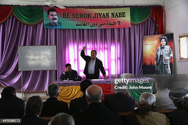 University professor Mahmoud Kali teaches ideological principals during a commune meeting at a Mala Gel or People's House under a portrait of PKK...