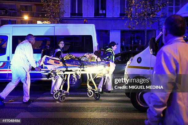 Rescuers evacuate an injured person on Boulevard des Filles du Calvaire, close to the Bataclan concert hall in central Paris, early on November 14,...
