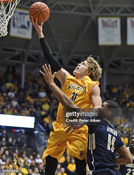 Guard Ron Baker of the Wichita State Shockers scores past forward Wesley Johnson of the Charleston Southern Buccaneers during the first half on...