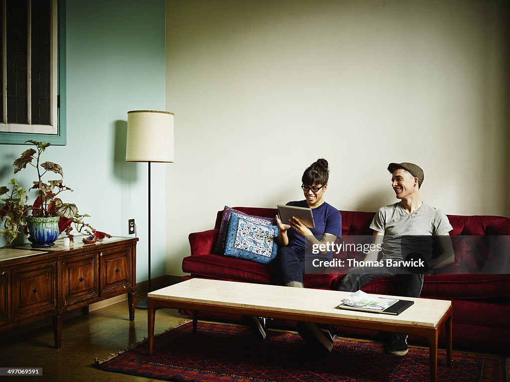 Smiling couple on couch working on digital tablet