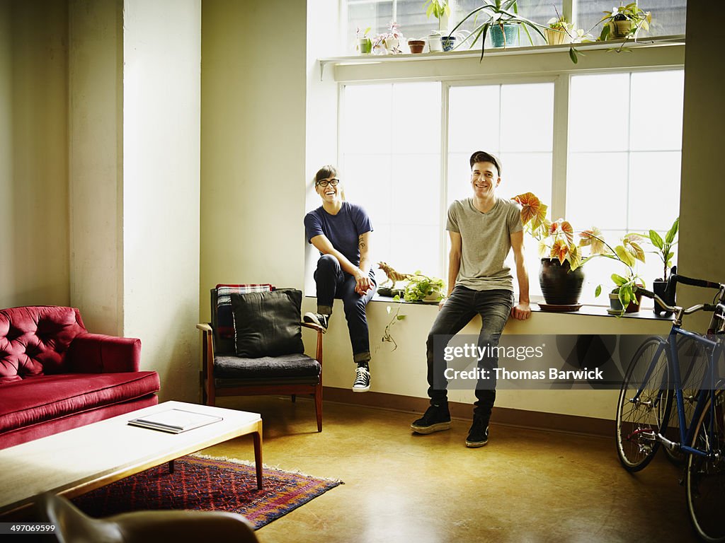 Laughing couple sitting on window sill in loft