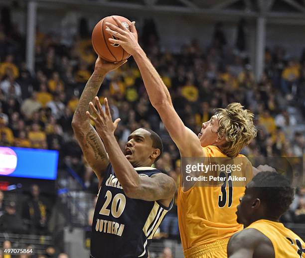 Guard Ron Baker of the Wichita State Shockers comes for behind to block the shot of guard Demetrius Pollard of the Charleston Southern Buccaneers...