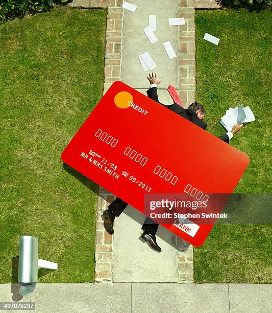 business man crushed under oversized credt card - high angle view stockfoto's en -beelden