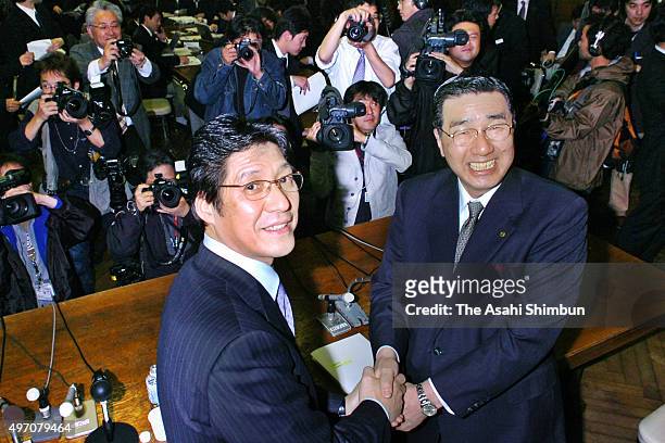 Matsuzakaya Holdings chairman Kunihiko Okada and Daimaru Department Store President Ryoichi Yamamoto shake hands during a press conference on their...
