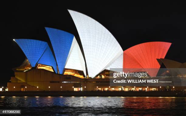 The iconic sails of the Sydney Opera House are lit in red, white and blue, resembling the colours of the French flag, in Sydney on November 14 as...