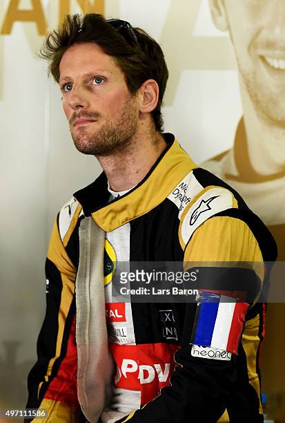 Romain Grosjean of France and Lotus wears a french national flag on his arm in tribute to the victims of the terrorist attacks in Paris as he stands...