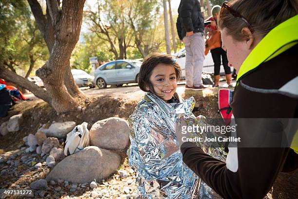 volunteer helping refugee girl on beach - migrant crisis in europe stock pictures, royalty-free photos & images