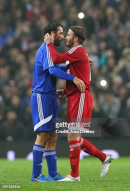 David Beckham of Great Britain and Ireland hugs Robert Pires of the Rest of the World as he is substituted in the second half during the David...