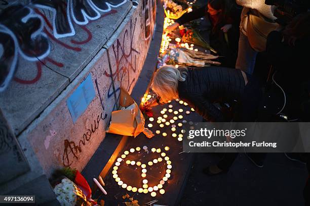 Parisians light candles and lay tributes on the monument at Place de la Republique, the day after deadly terrorist attacks on November 14, 2015 in...