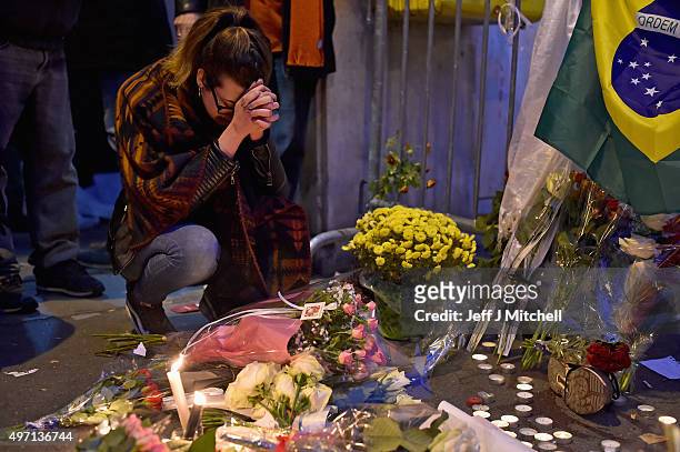 Woman prays as people place flowers and candles on the pavement near the scene of yesterday's Bataclan Theatre terrorist attack on November 14, 2015...