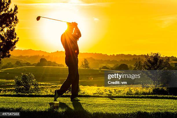 golfer bei sonnenuntergang - abschlagen stock-fotos und bilder