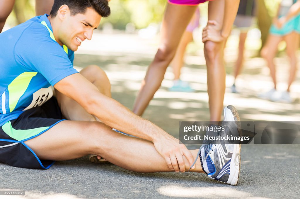 Mann leiden Knöchel Schmerzen auf der Straße beim Marathon