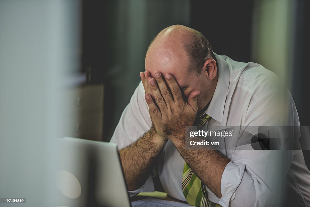 Frustrated office worker with his head in his hands