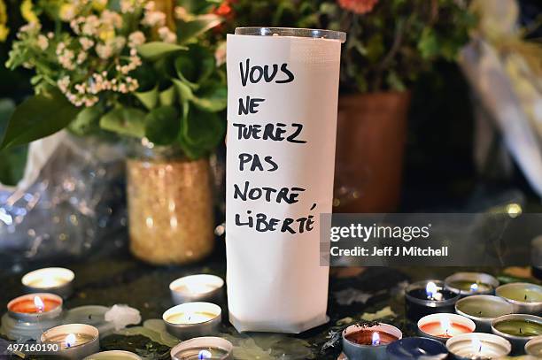 Flowers and candles are left on the pavement near the scene of yesterday's Bataclan Theatre terrorist attack on November 14, 2015 in Paris, France....