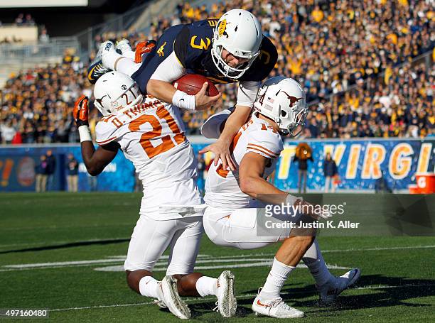 Skyler Howard of the West Virginia Mountaineers attempts to hurdle Duke Thomas and Dylan Haines of the Texas Longhorns in the second half during the...