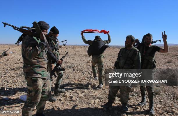 Member of the Syrian pro-government forces holds up the Syrian national flag as troops gather on a hilltop they reported took over overlooking the...