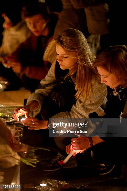 Woman lights a candle at a spontaneous gathering of Parisians at Place de la Republique on November 14, 2015 in Paris, France. At least 120 people...