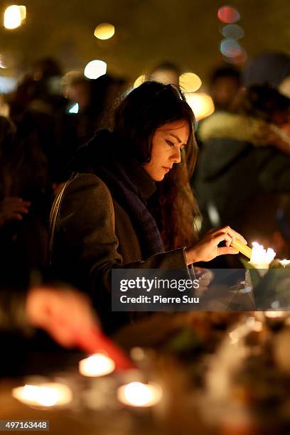 Woman lights a candle at a spontaneous gathering of Parisians at Place de la Republique on November 14, 2015 in Paris, France. At least 120 people...