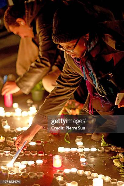 Woman lights a candle at a spontaneous gathering of Parisians at Place de la Republique on November 14, 2015 in Paris, France. At least 120 people...