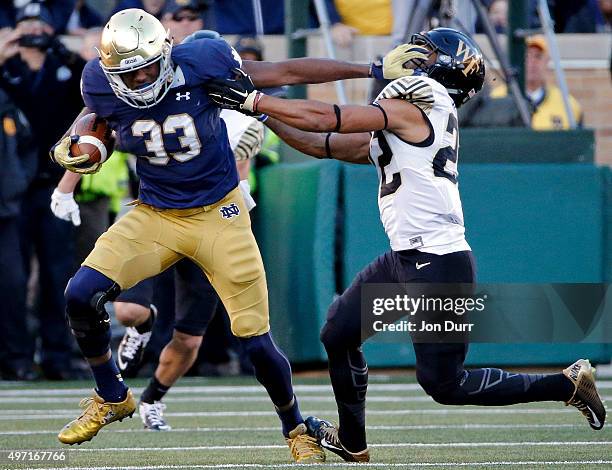 Josh Adams of the Notre Dame Fighting Irish stiff arms Ryan Janvion of the Wake Forest Demon Deacons on his 98-yard rushing touchdown during the...