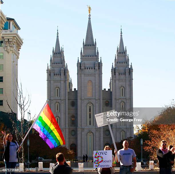 Protesters hold signs and a pride flag in front of the historic Mormon temple after many submitted their resignations from the Church of Jesus Christ...