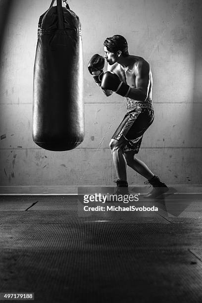 homem hispânico chutando um saco de pancadas, em preto e branco - esporte de combate - fotografias e filmes do acervo