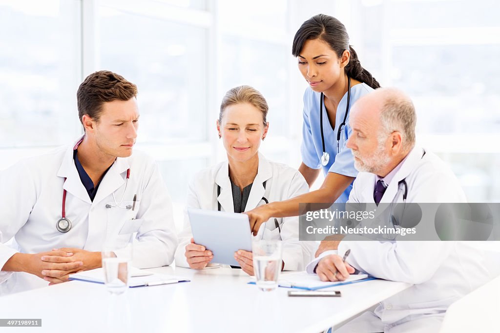 Multiethnic Medical Team Using Digital Tablet At Table