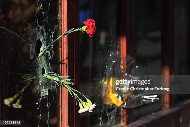 Flower is placed inside a bullet hole in the window of Le Carillon restaurant in tribute to the victims of the terror attacks on November 15, 2015 in...