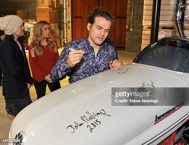 Reid Perry, Kimberly Perry and Neil Perry of The Band Perry autograph a Porsche tractor at the GRAMMY Foundation house concert featuring The Band...