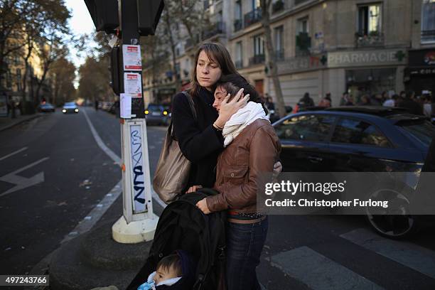 People react as they view tributes and flowers outside La Belle Equipe restaurant on Rue de Charonne following Fridays terrorist attack and France...