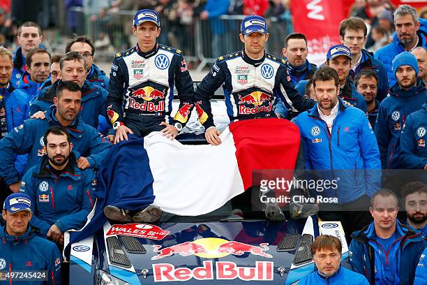Sebastien Ogier and Julien Ingrassia of France and Volkswagen Motorsport team members pose with the French tricolor as a mark of respect for the...