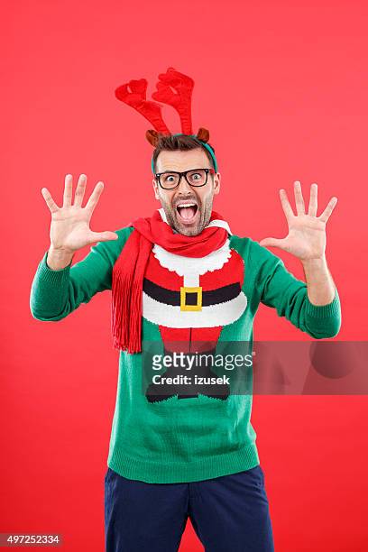 shocked nerd man in funny winter outfit against red background - christmas jumper stock pictures, royalty-free photos & images