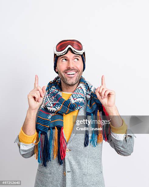 happy handsome man in winter outfit pointing at copy space - ski goggles stockfoto's en -beelden