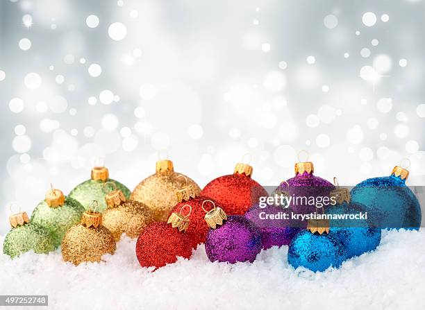 multicolor glitter decorated baubles in a row lying on snow - high key stock pictures, royalty-free photos & images