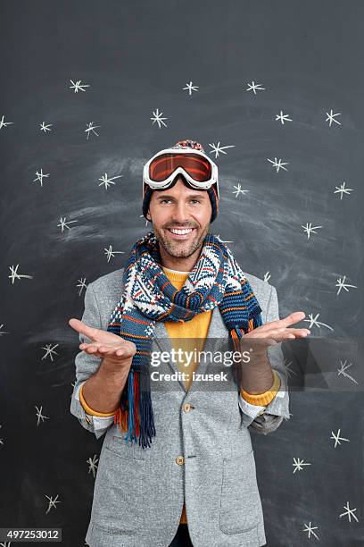 pleased man in winter outfit against blackboard - ski wear stock pictures, royalty-free photos & images