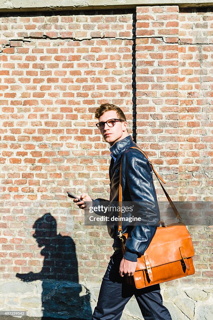 Young student with shoulder bag and smartphone