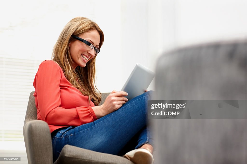 Heureuse jeune femme portant lunettes à l'aide de tablette