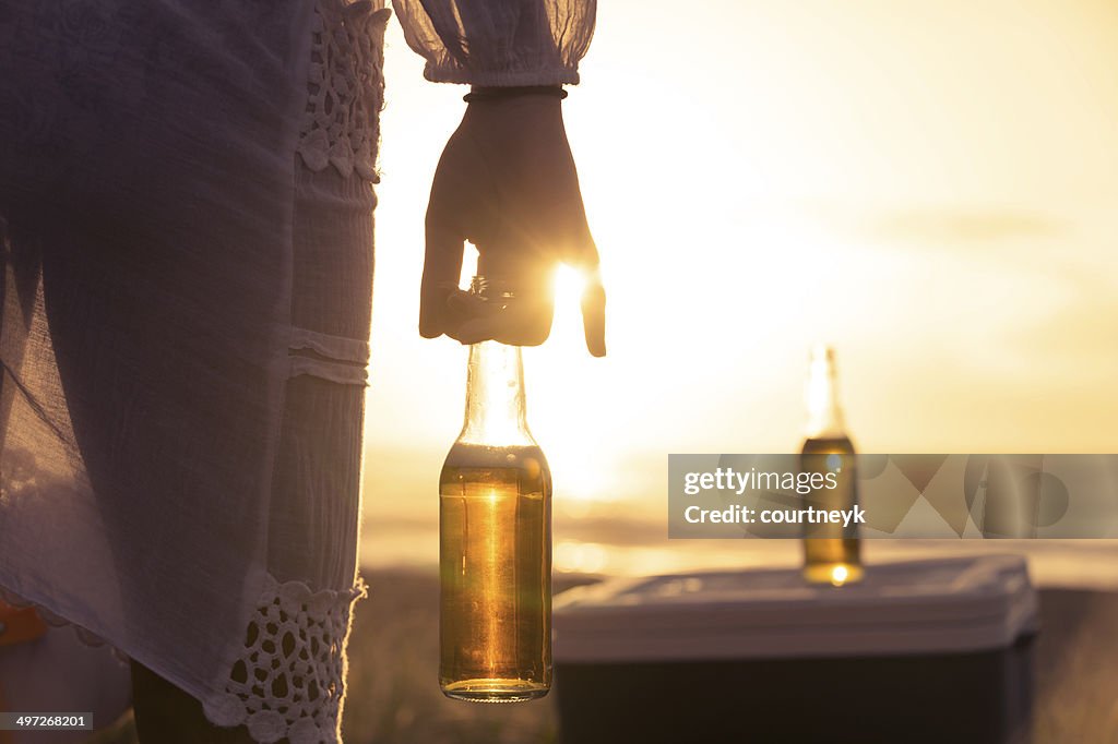 Woman drinking beer on the beach