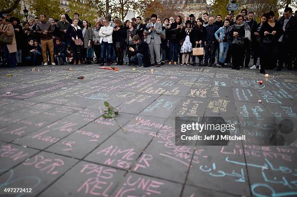 People gather and view messages written on the ground at Place de la Republique on November 15, 2015 in Paris, France. As France observes three days...