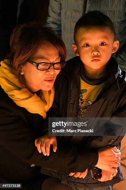 Woman holds a child as candles are lit near the Bataclan theatre as France observes three days of national mourning on November 15, 2015 in Paris,...