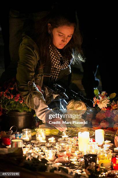 Woman lights a candle near the Bataclan theatre as France observes three days of national mourning on November 15, 2015 in Paris, France. Members of...