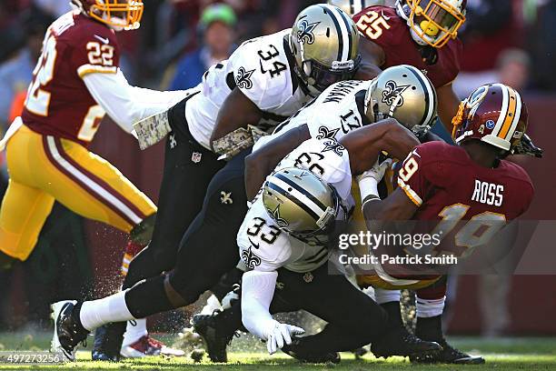 Rashad Ross of the Washington Redskins is tackled by Jamarca Sanford and T.J. Graham of the New Orleans Saints in the first half at FedExField on...