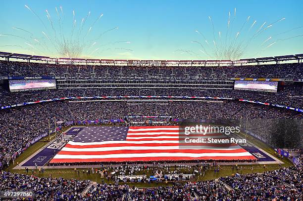 The United States flag covers the field during the National Anthem prior to the game between the New York Giants and the New England Patriots at...