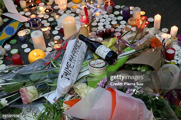 Bottle of red wine, a French baguette and a camembert cheese are placed near the floral tributes near the "Bataclan" on November 15, 2015 in Paris,...