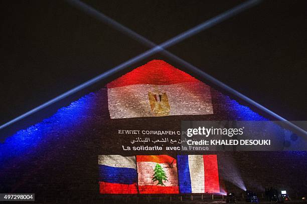 Picture taken on November 15, 2015 shows the great pyramid of Khufu illuminated with the French, Lebanese and Russian flags in Giza, outskirt of...