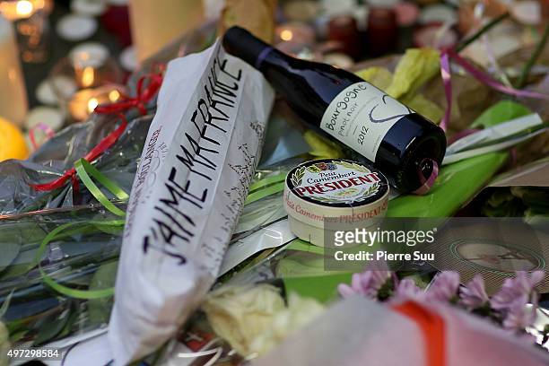 Bottle of red wine, a French baguette and a camembert cheese are placed near the floral tributes near the "Bataclan" on November 15, 2015 in Paris,...