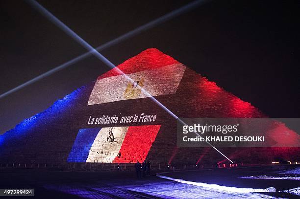 Picture taken on November 15, 2015 shows the great pyramid of Khufu illuminated with the French flag in Giza, outskirt of Cairo, during a ceremony in...